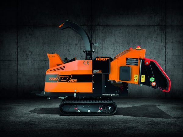 Side view of orange Först TR8 tracked wood chipper with closed feed hopper inside a dark warehouse