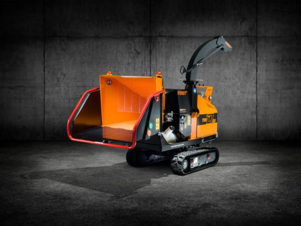 Orange Först TR8 wood chipper with large open feed hopper and tracked base inside a dark industrial environment