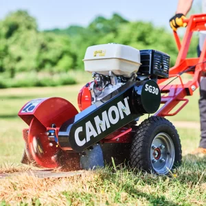 Red CAMON SG30 stump grinder machine with engine grinding a tree stump on grass
