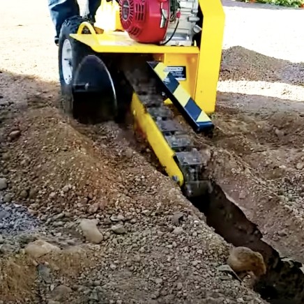 Small walk-behind trencher digging a narrow trench in the soil