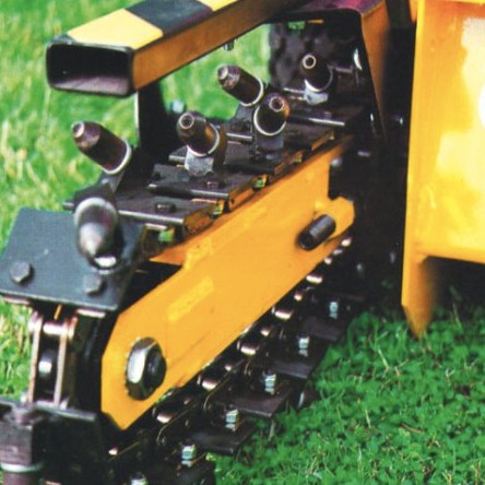 Close-up of yellow trencher chain mechanism on grass