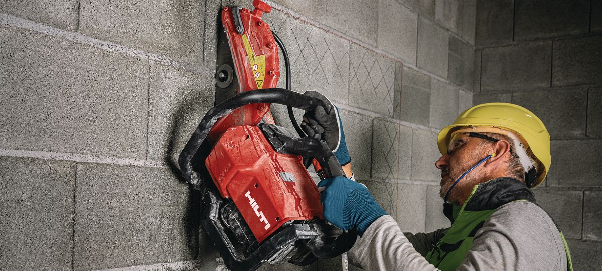 hilti 3 Worker wearing safety gear using a red Hilti disc cutter to cut a vertical concrete wall