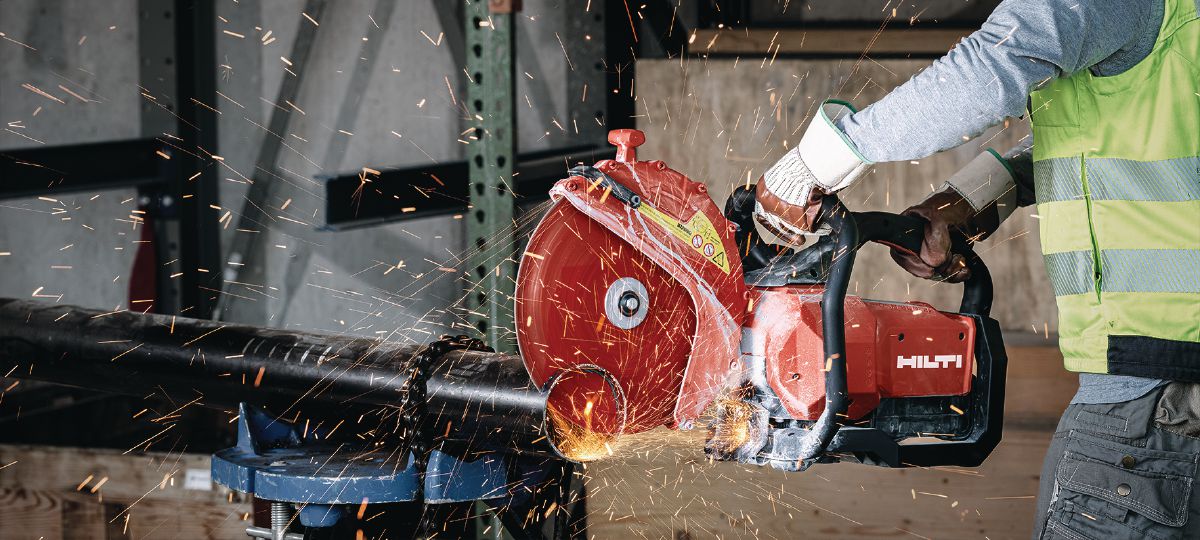 hilti 4 Worker operating a red Hilti disc cutter, cutting a metal pipe with sparks flying, wearing a safety vest